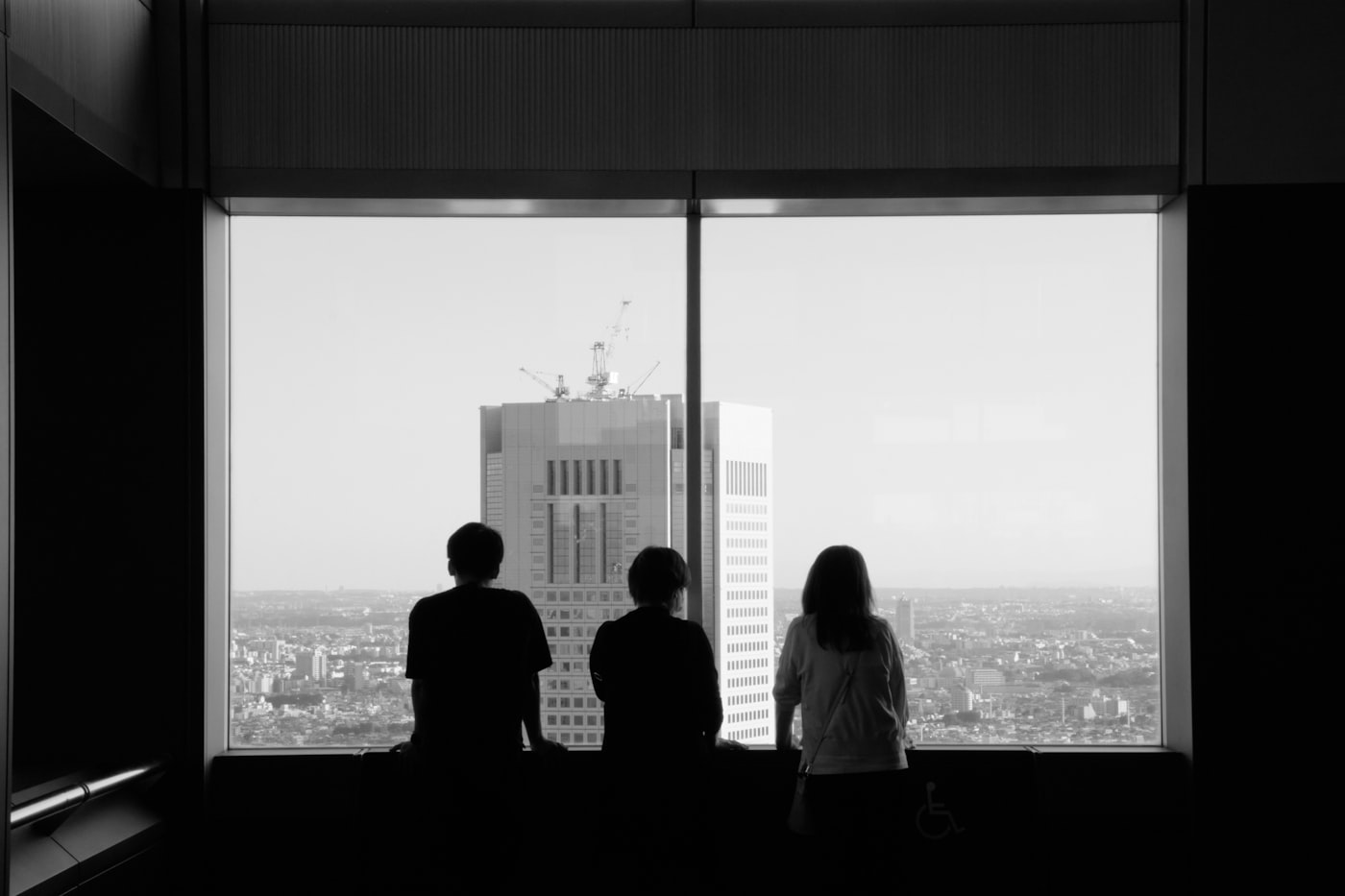 Three figures reading the skyline from a high window